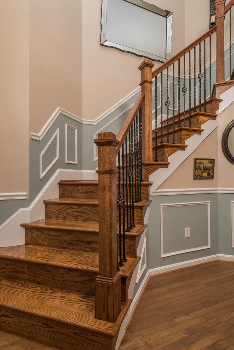Staircase with iron balusters, wainscoting and hardwood treads